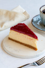 Cheesecake on white background. Greek sweet dessert concept. plate of sliced cheesecake. Cheesecake with raspberry gel filling. Mediterranean bakery. close up. selective focus. Vertical view.