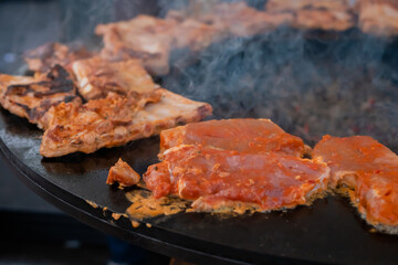 Process of cooking fresh juicy meat steaks on brazier at summer local food market - close up view. Outdoor cooking, gastronomy, cookery, street food concept