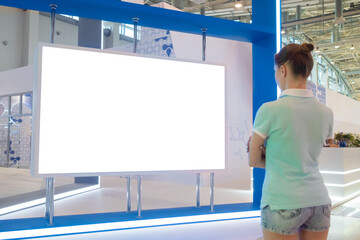 Woman looking at blank digital interactive white display wall at exhibition or museum with...