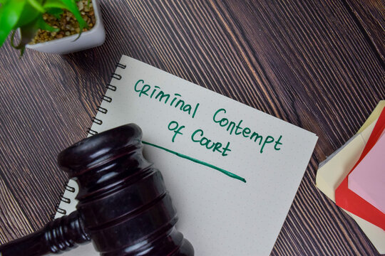 Criminal Contempt Of Court Write On A Book Isolated On Wooden Table.