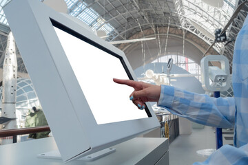 Woman hand touching blank interactive touchscreen white display of electronic kiosk at futuristic exhibition or museum: close up. White screen, mock up, copyspace, template, technology concept.