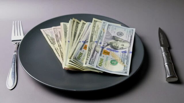 U.S. dollars served on a plate with knife and fork.