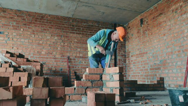 A builder on a construction site puts bricks in the house. Builder brickwork ventilation duct.