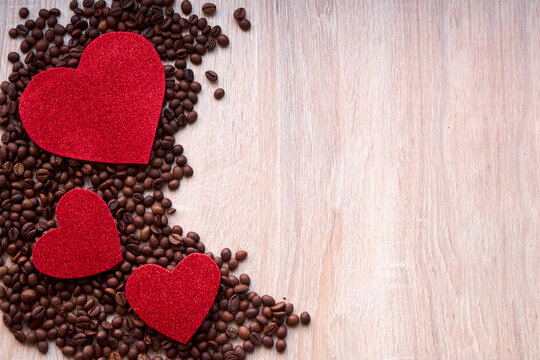 Valentine day concept with red hearts and coffee beans on wooden table with copyspace.Coffee beans and heart in the coffee lover concept