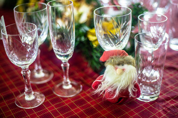 Wonderful table for the celebration of Christmas set up with plates, glasses, wine glasses, and golden cutlery with ornaments in red tones. Christmas ornaments on the table.