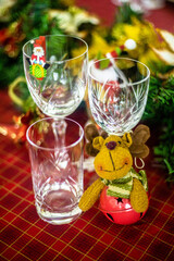 Wonderful table for the celebration of Christmas set up with plates, glasses, wine glasses, and golden cutlery with ornaments in red tones. Christmas ornaments on the table.