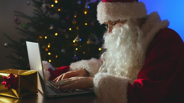 Santa claus is typing a letter on the computer.