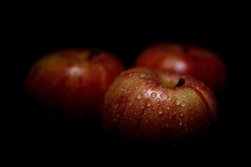 three red apples on black background