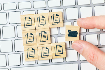 Concept document management system or DMS. The person archives files in a folder. Hand and cubes on...