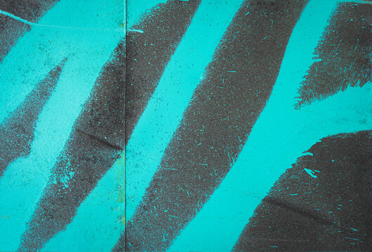 Street art detail. Neon green turquoise spray paint pattern on dark black metal panel wall texture background. Paint splash. Creative, stylish urban backdrop. Painted, old, aged, weathered structure