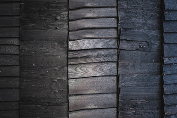 Black burnt wooden texture background. Beautiful, stylish boards pattern with optical illusion of movement and ombre effect. Igloo sauna or house exterior design. Harsh wood without finish. Copy space