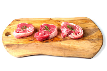 Three fresh lamb loin chop with herbs on a wooden board and white background. Meat industry product, butcher craft and skill example. Top quality meat.