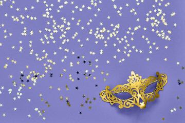 Fototapeta premium Golden carnival mask and golden stars on lilac very peri background. Carnival celebration concept.