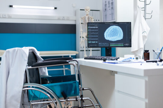 Modern empty hospital office having computer with brain radiography on screen ready for oncology examination. Cabinet room equipped with medical professional tools. Brain tomography image