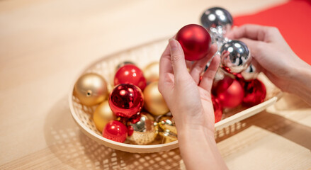 Female hands holding christmas red ball for decorated on the Christmas tree.