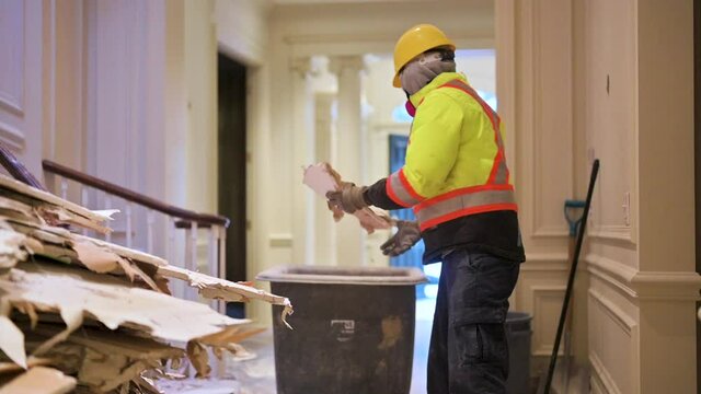 Anonymous Demolition Labourer in full PPE collecting thrown out materials from house