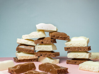 Turrets made of slices of black and white chocolate on a beige background. Slices from a bar of chocolate.
