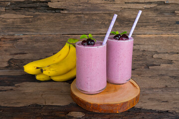 Blueberry mix banana smoothies purple colorful fruit juice milkshake blend beverage healthy high protein taste yummy drink in glass morning on wooden background.