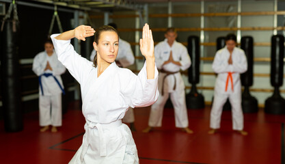 Woman in kimono is practicing karate moves at gym