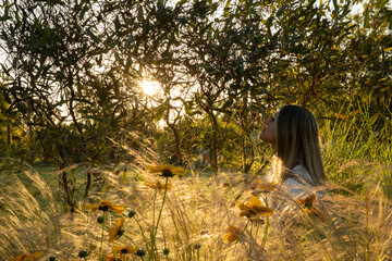 Portrait of young woman laying in the field at sunset. Coreopsis grandiflora yellow flowers and...