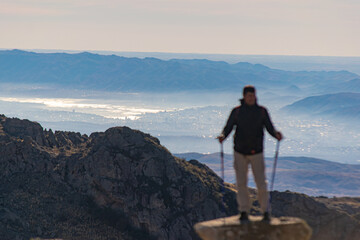 Fototapeta premium bush person trekking on a mountain with landscape behind