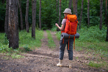 Obraz premium Young caucasian woman is hiking and using a compass in the forest.