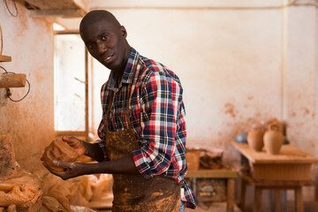 African American craftsman making pot in workshop, moulding wet clay