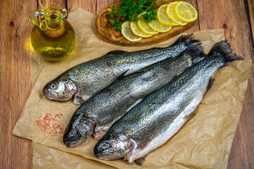 Three raw trout ready to be cooked with sea salt, olive oil, lemons and parsley. 