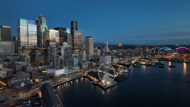 Cinematic 4K aerial drone night trucking shot of Alaskan Way waterfront with  Pike Place, The Seattle Great Wheel, Aquarium by Elliott Bay, Lumen Field downtown Seattle Washington