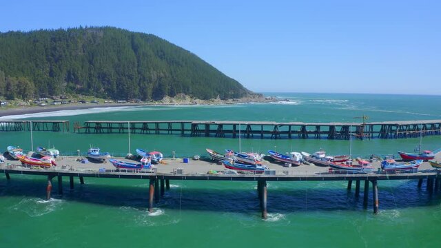 port or caleta meguellines, constitucion chile drone shot sunny day with fishing boats traveling left