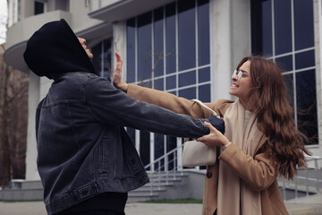 Woman fighting with thief while he trying to steal her bag on city street. Self defense concept