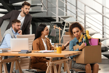 Young dismissed woman with stuff into box at office