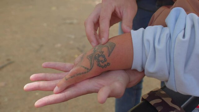 A social worker doing massage to a disabled person. Close up of hand with tattoo without fingers. Congenital amputations of limbs and health care.