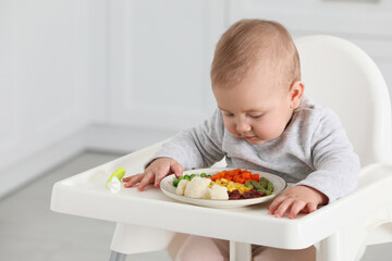 Cute little baby eating healthy food at home
