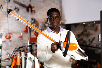 Portrait of man with an brush cutter in hardware store