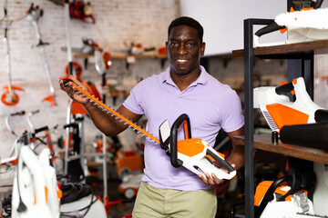 Adult serious man with an brush cutter in hardware store