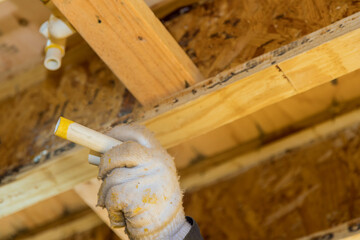 Plumber jointing glue PVC water pipes on a house under construction