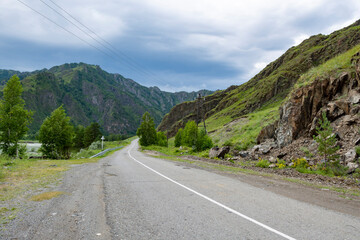 The paved road between steep mountain peaks goes into the distance