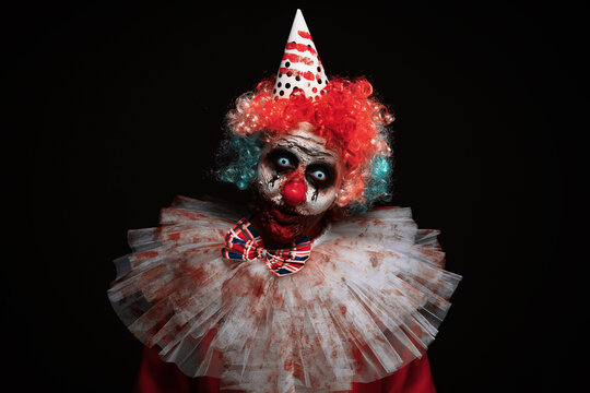 Terrifying clown on black background. Halloween party costume