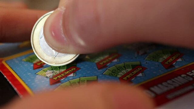 caucasian person plays a scratch card with one euro coin close up - gambling addiction concept