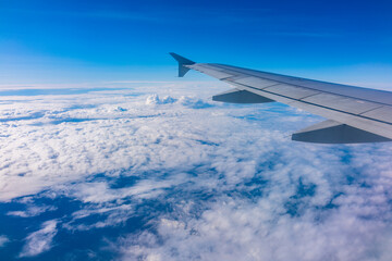 View from the airplane window at a beautiful cloudy sky and the airplane wing