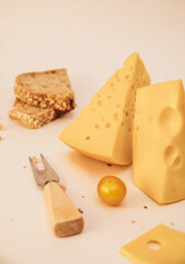 cheese, bread and vegetables on the table. two pieces of fresh cheese. cheddar and emmental on the table. cheese sandwich on the table