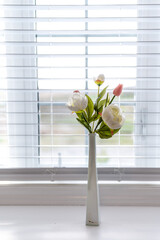 white flowers by window blinds in the background 