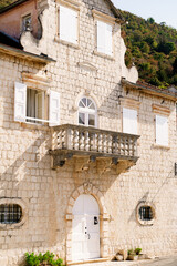 Fototapeta na wymiar Facade of a stone building with shutters and a balcony. Perast, Montenegro