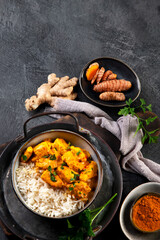 Indian butter chicken curry with basmati rice on dark background.