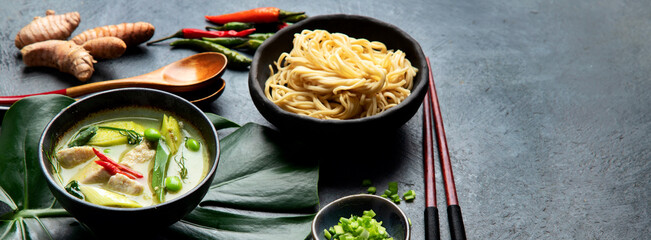 Green curry with chicken in bowl on dark background.