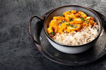 Indian butter chicken curry with basmati rice on dark background.