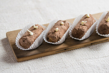 Traditional russian chocolate potato cake on a wooden board on linen tablecloth. Horisontal, selective focus