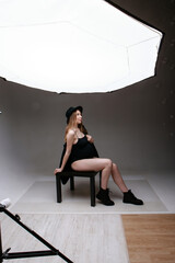 a pregnant woman in a black suit strokes her belly on a white background. A girl in the studio in the spotlight. professional lighting.