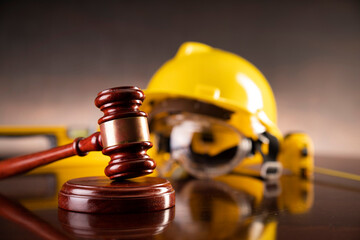 Labour law and builiding law concept.  Gavel and yellow crash helmet on the shining lawyer desk.